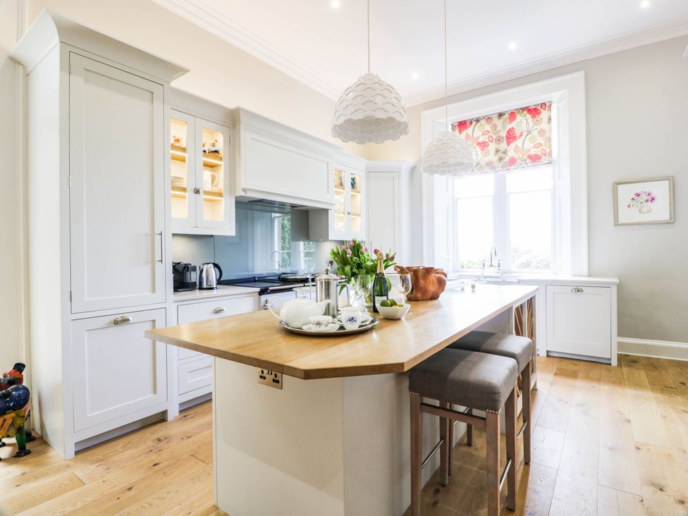 A kitchen with an island, stools, and a window at Eagle Glen Manor House in Blairgowrie