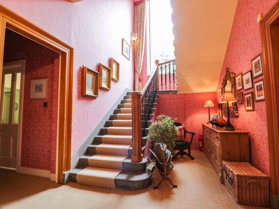 A hallway with staircase and pictures on the wall at Eagle Glen Manor House in Blairgowrie