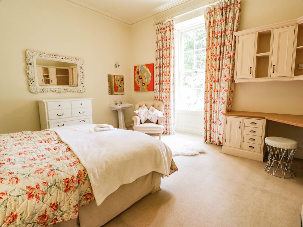 A bedroom with a bed and a dressing table at Eagle Glen Manor House in Blairgowrie