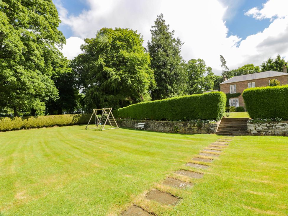 A garden with a swing set and hedge at Eagle Glen Manor House in Blairgowrie