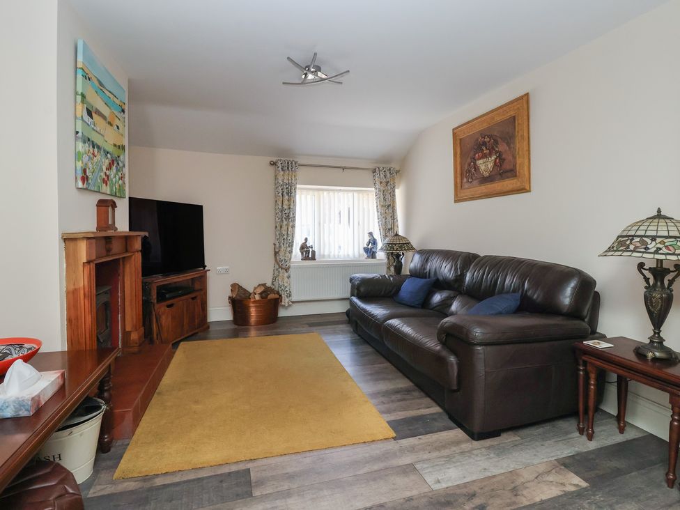 A living room with a brown leather sofa a wooden fireplace a television and a yellow rug at 4 Queen Street in Withernsea