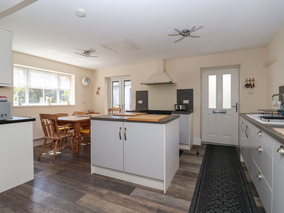 A kitchen with a central island, wooden dining table and chairs, and white cabinets at 4 Queen Street in Withernsea