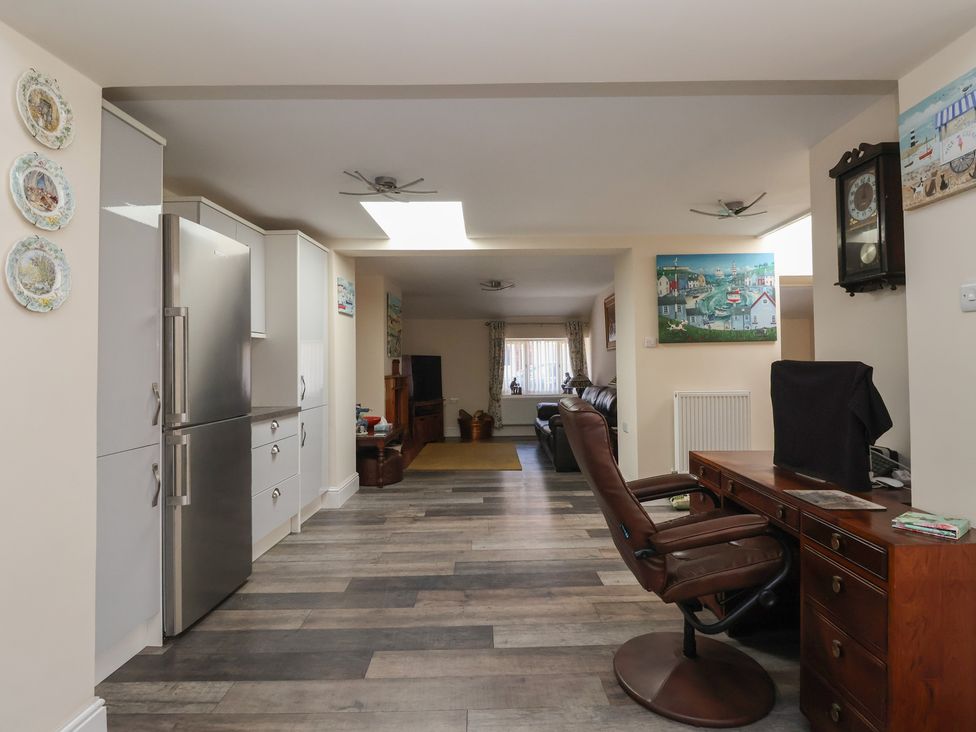 An open plan kitchen and living area with a stainless steel fridge desk with office chair and wall clock at 4 Queen Street in Withernsea