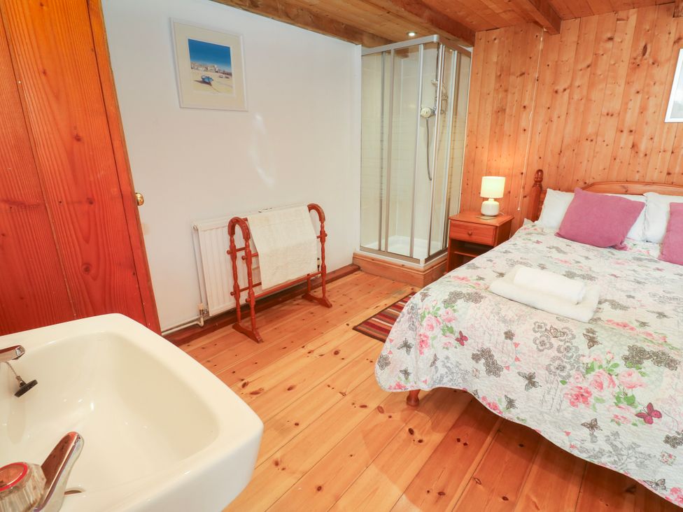A bedroom with a bed and a shower at The Cottage in St. Ives