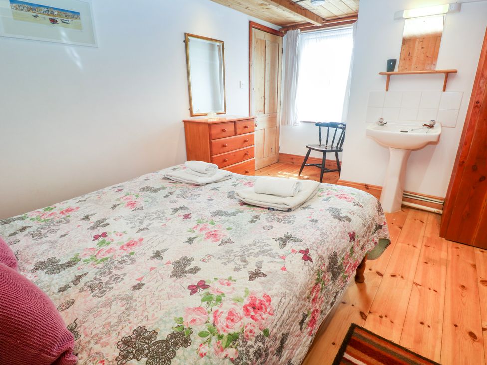 A bedroom with a bed and dresser at The Cottage in St. Ives