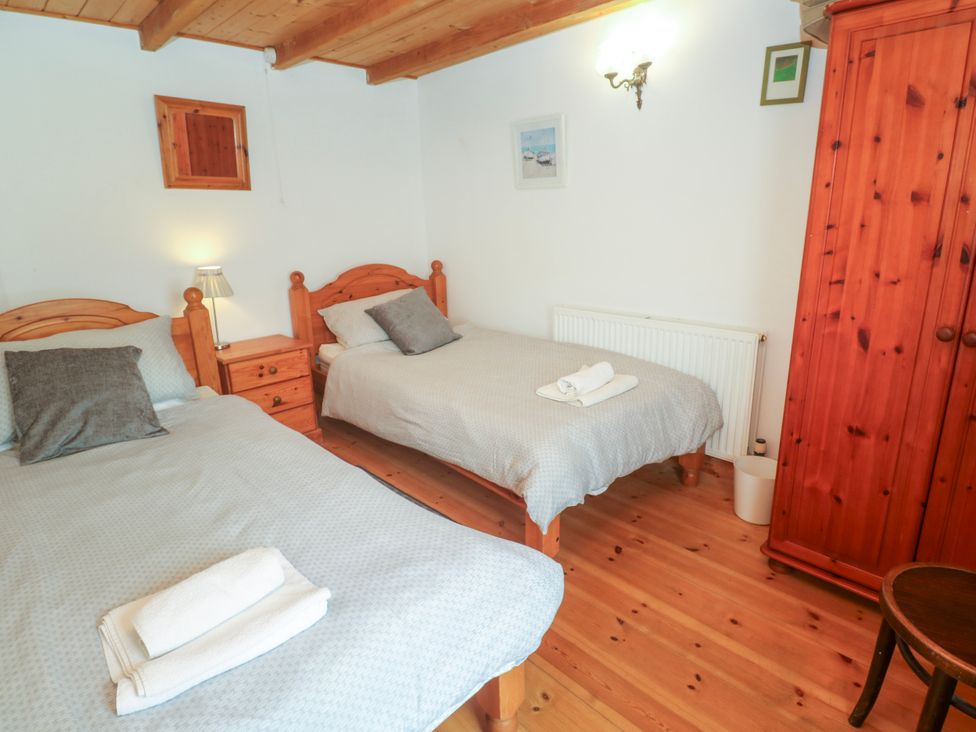 A bedroom with two beds and wooden furniture at The Cottage in St. Ives