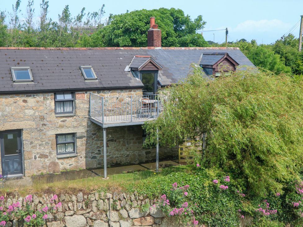 A stone building with a balcony and flowers at The Cottage in St. Ives