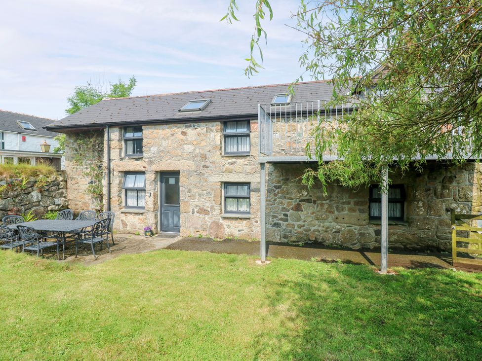 An outdoor area with a stone house and a metal table at The Cottage in St. Ives
