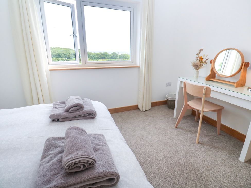 A bedroom with a bed and a desk with a mirror at Swallows Nest in St. Ives