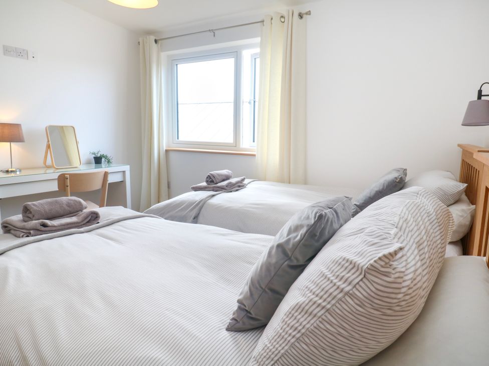 A bedroom with two beds and a desk at Swallows Nest in St. Ives