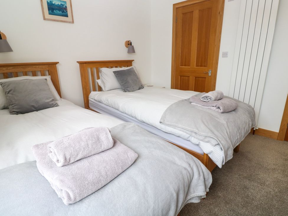 A bedroom with two single beds and towels at Swallows Nest in St. Ives