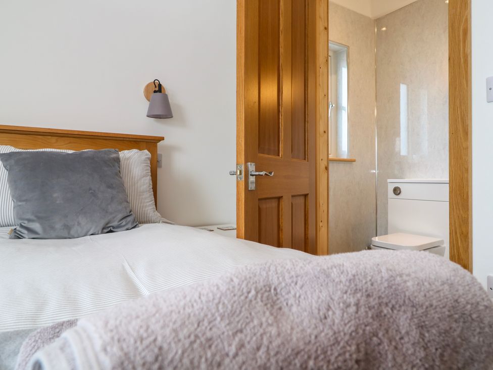 A bedroom with a bed and a bathroom in view at Swallows Nest in St. Ives