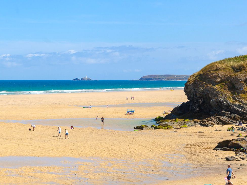A beach with people and a rocky cliff at Swallows Nest in St. Ives