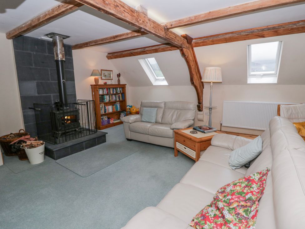 A living room with a wood stove and bookshelves at Yr Hen Ysgoldy