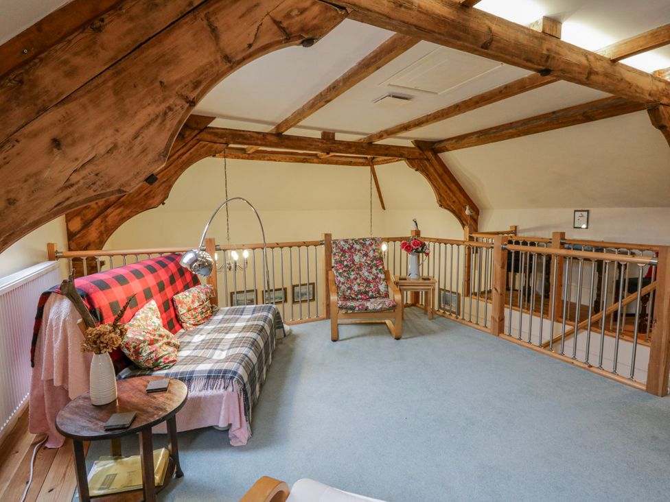 A loft area with a sofa, armchair and table at Yr Hen Ysgoldy 
