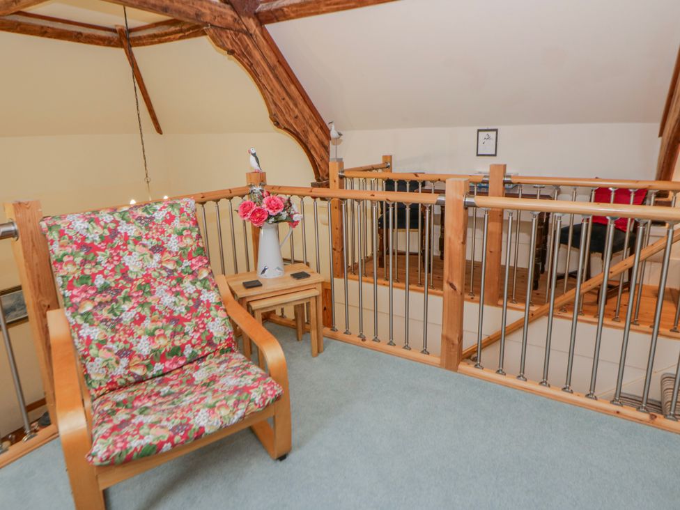A seating area with a chair and table in a loft space at Yr Hen Ysgoldy