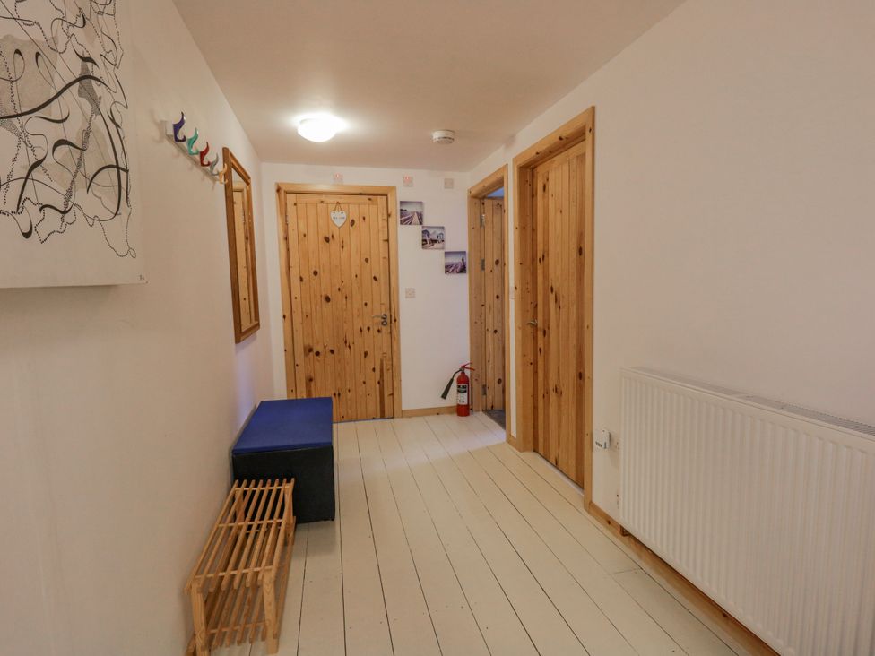 A hallway with wooden doors and a bench at Yr Hen Ysgoldy