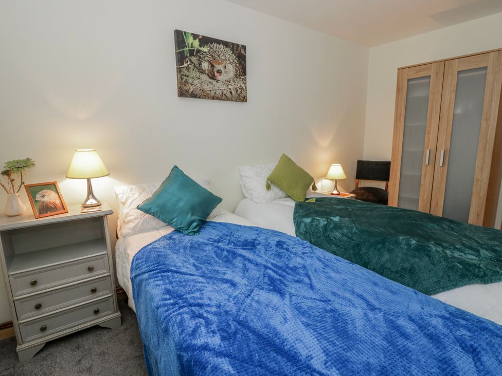 A bedroom with two beds and a lamp at Yr Hen Ysgoldy in 