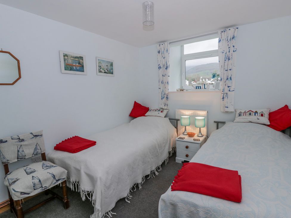 A bedroom with two beds and a bedside table at Yr Hen Ysgoldy