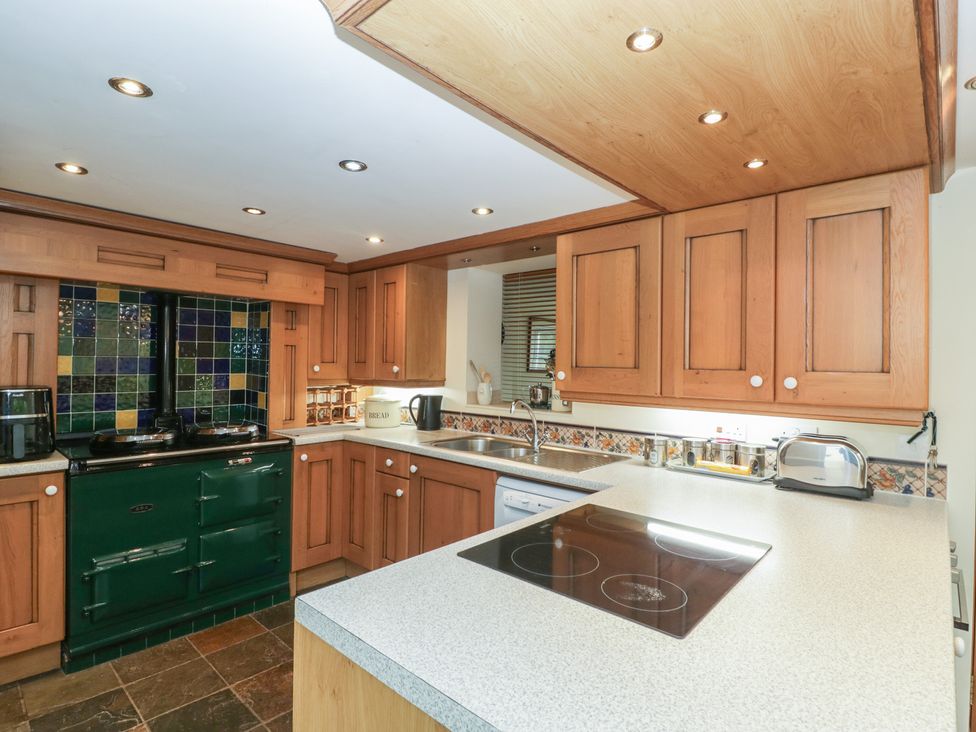 A kitchen with wooden cabinets and a green oven at Wren Cottage in Ross-on-Wye