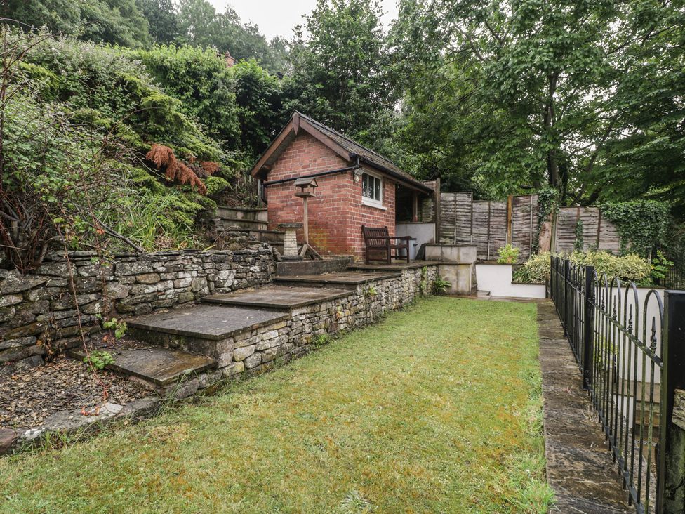 A garden with a brick building and steps at Wren Cottage in Ross-on-Wye