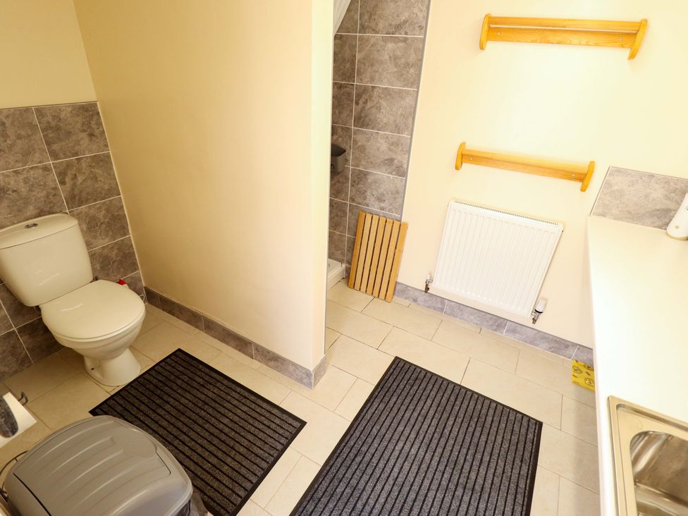 A bathroom with a toilet, sink, and wall shelves at Lancaster in Lincoln