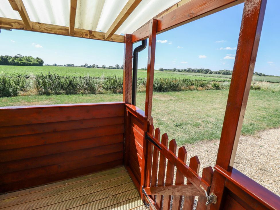 A wooden fence with a gate overlooking grassy fields at Lancaster in Lincoln