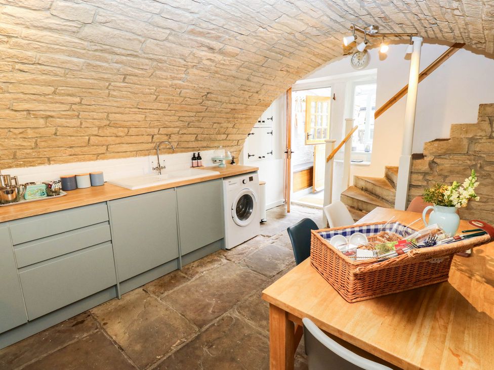 A kitchen with a washing machine and dining table at Winberry Cottage in Haworth