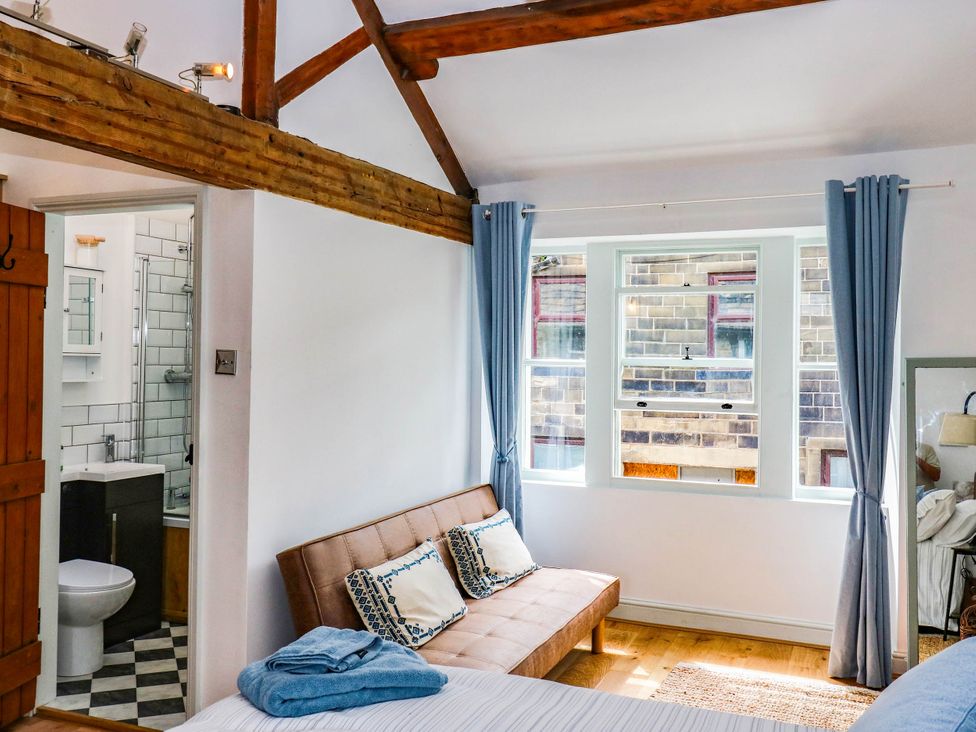 A bedroom with a bed and bathroom door at Winberry Cottage in Haworth