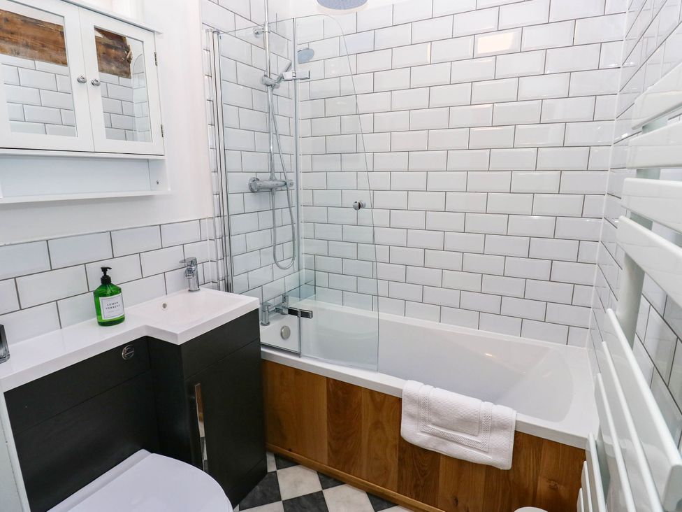 A bathroom with a bathtub, shower, and sink at Winberry Cottage in Haworth