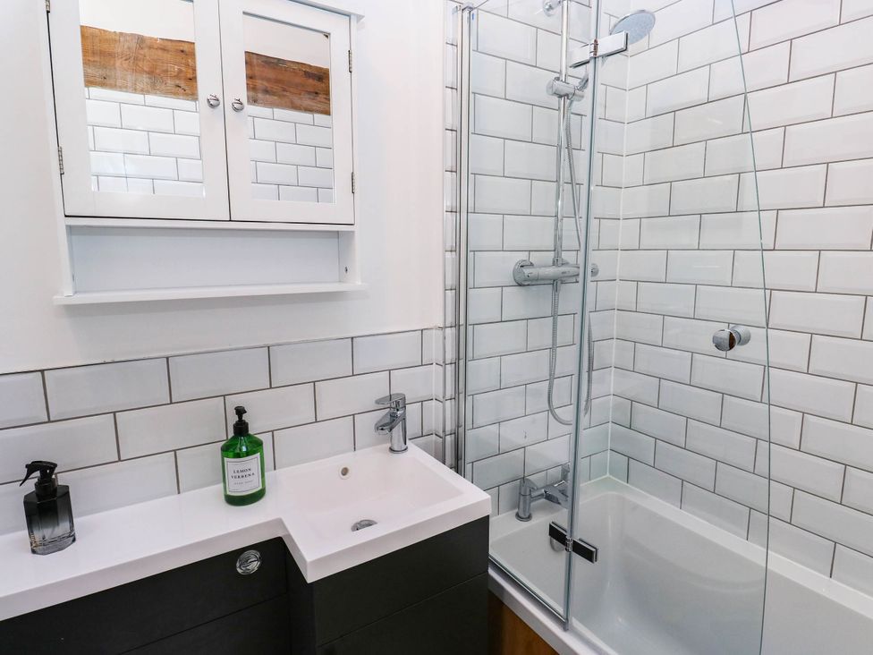A bathroom with a shower, bath, and sink at Winberry Cottage in Haworth