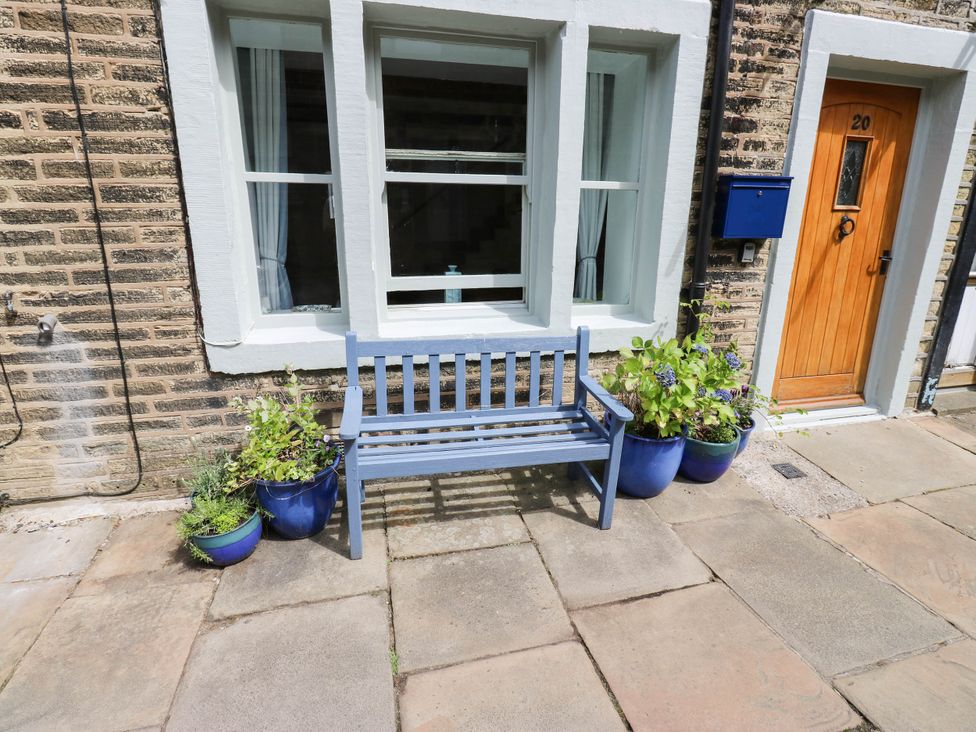An outdoor space with a bench, plants, and a door at Winberry Cottage, Haworth