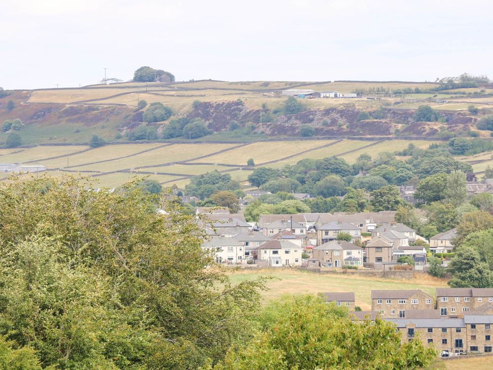 A view of houses and fields with hills in the background at Winberry Cottage in Haworth