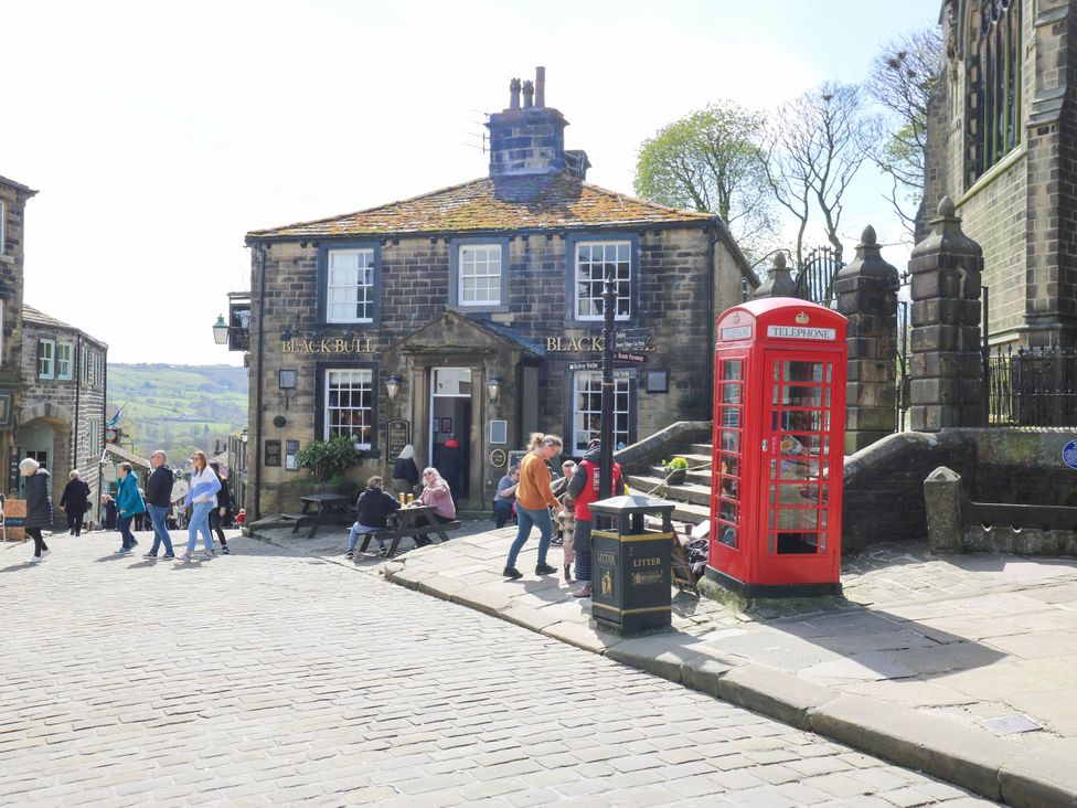 A pub with a classic telephone box and people outside at Winberry Cottage Haworth