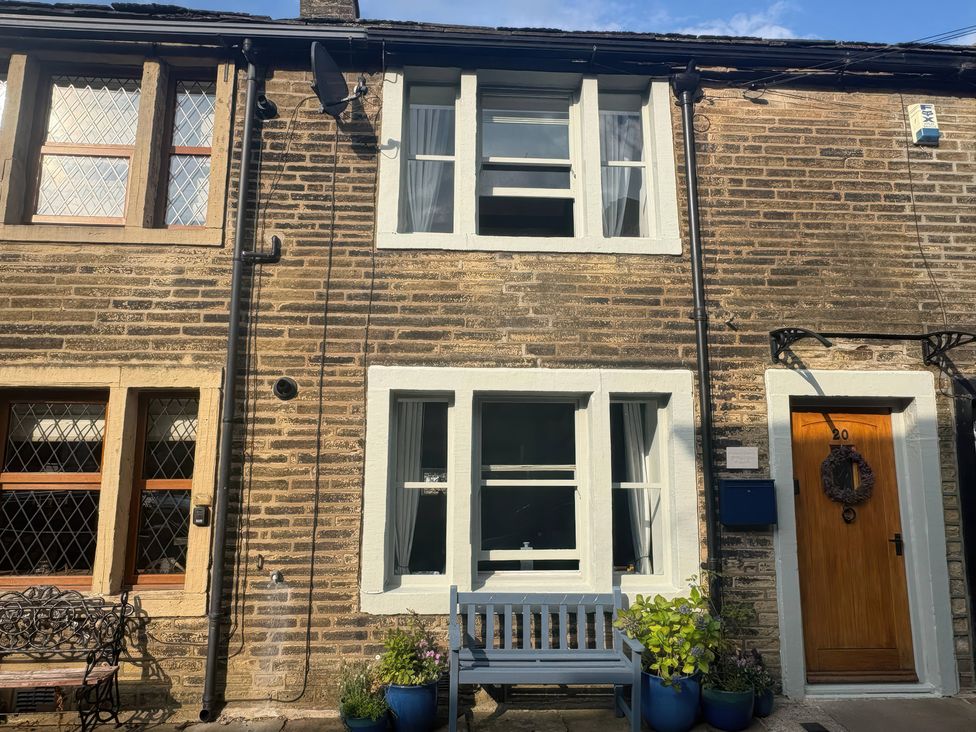 An outdoor view of a house with windows and a bench at Winberry Cottage in Haworth