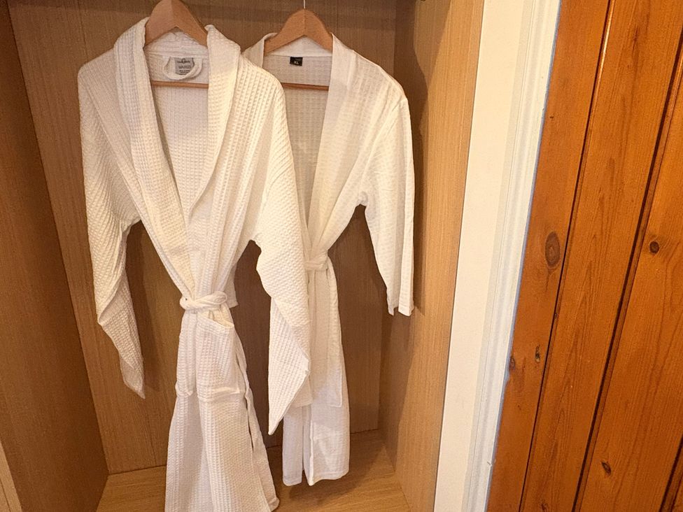 Two white bathrobes hanging in a closet at Winberry Cottage in Haworth