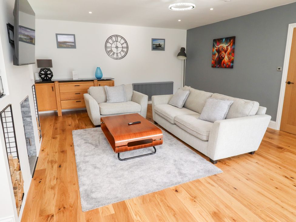 A living room with a sofa, coffee table, and television at Rose Cottage in Dunstan near Embleton