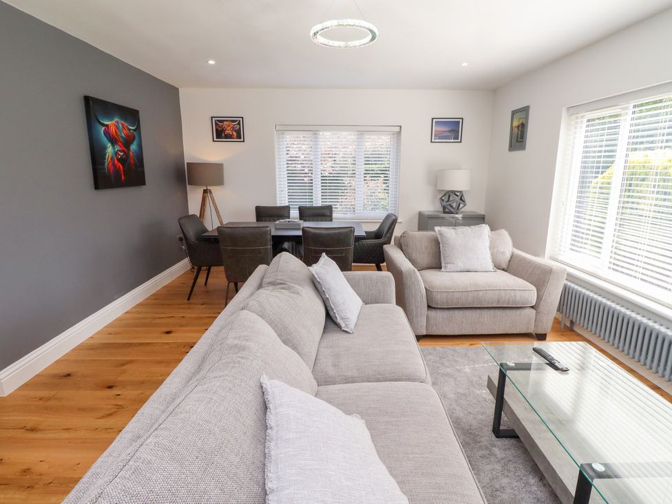 A living room with a sofa, armchair, and dining table at Rose Cottage in Dunstan near Embleton