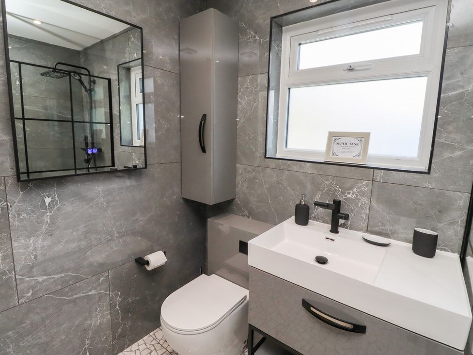 A bathroom with a shower and washbasin at Rose Cottage, Dunstan near Embleton