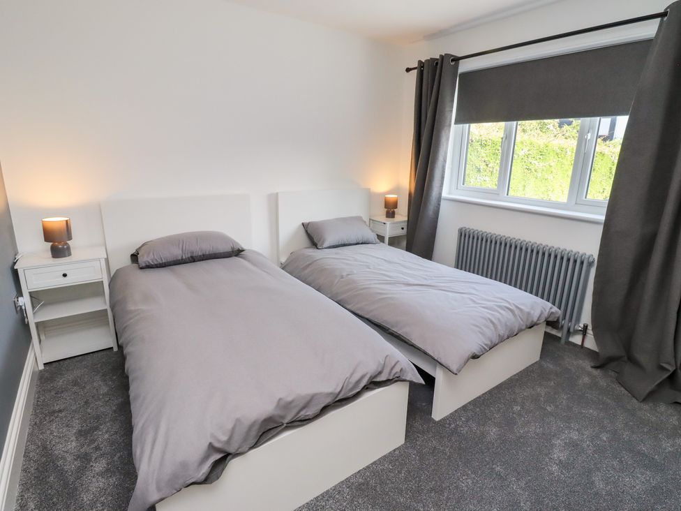A bedroom with twin beds and bedside table at Rose Cottage Dunstan near Embleton