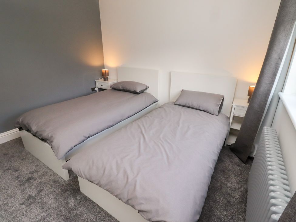 A bedroom with two single beds and bedside tables at Rose Cottage Dunstan near Embleton