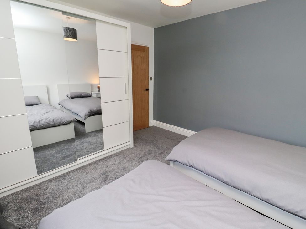 A bedroom with beds and wardrobe at Rose Cottage Dunstan near Embleton
