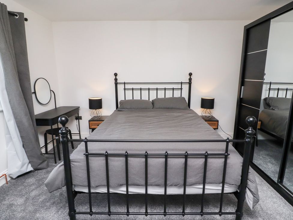 A bedroom with a bed, nightstand, lamp and desk at Rose Cottage in Dunstan near Embleton