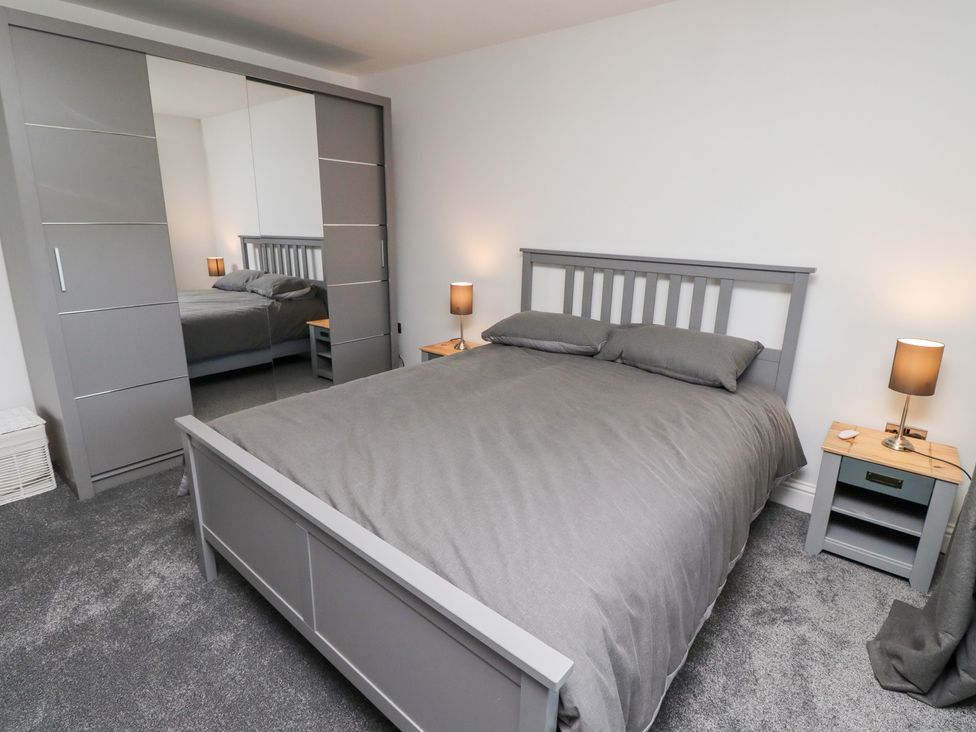 A bedroom with a bed and wardrobe at Rose Cottage in Dunstan near Embleton