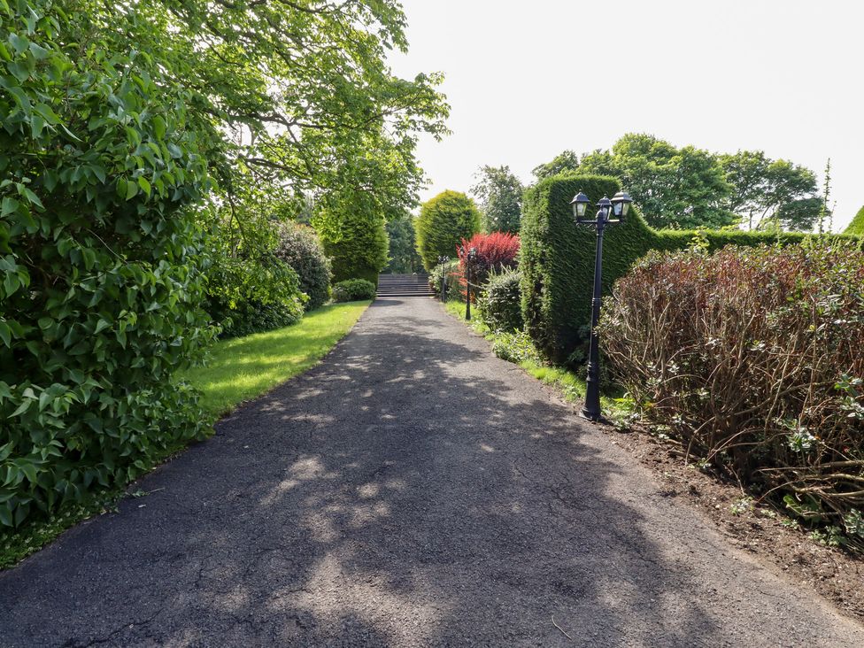 A pathway lined with hedges and trees at Rose Cottage in Dunstan near Embleton