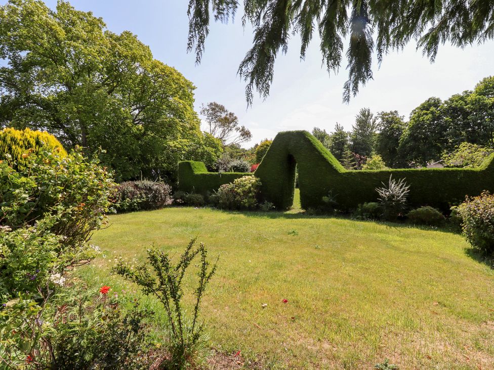 A garden with a hedge and flower beds at Rose Cottage in Dunstan near Embleton
