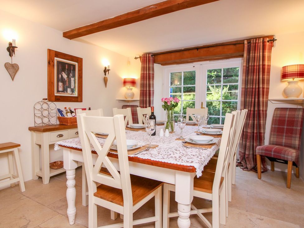 A dining room with a table set for six and plaid curtains at Church Thatch Abbotskerswell