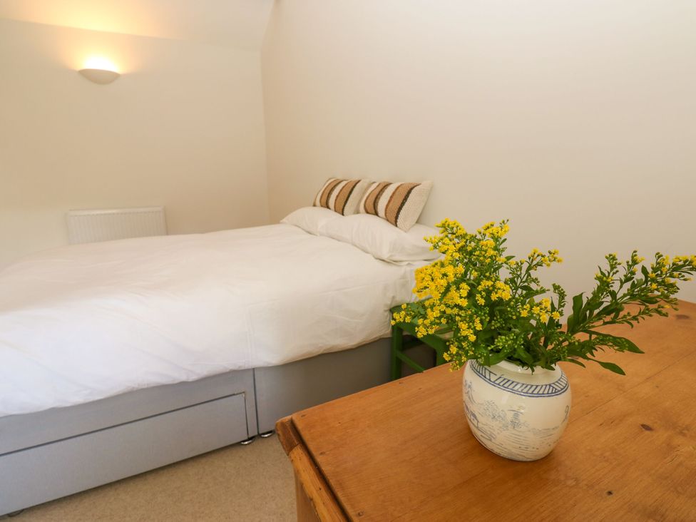 A bedroom with a bed, table, and vase of flowers at High Meadow Barn near Thornton Rust