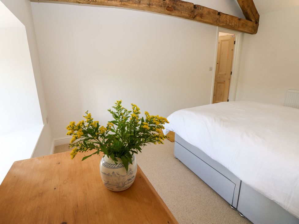 A bedroom with a bed and flowers on a table at High Meadow Barn Thornton Rust near Bainbridge