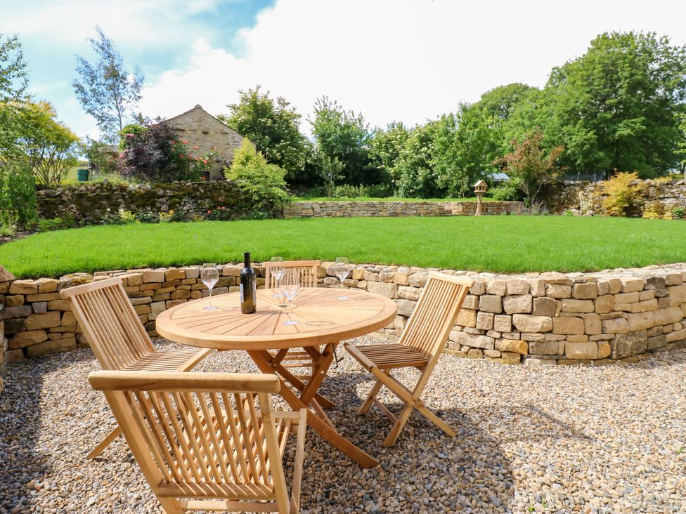 A garden with a wooden table and chairs at High Meadow Barn Thornton Rust near Bainbridge